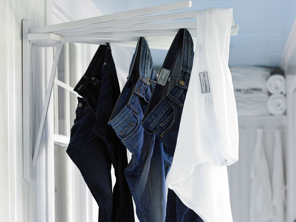 Four pairs of denim jeans dry on a clothesline after being washed with The Laundress fabric care products.