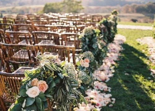 4354_one_size_image_01_6997 A wedding aisle with wooden chairs, greenery, and flowers.