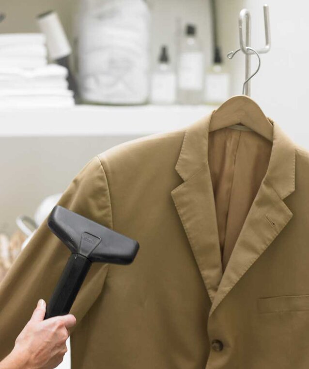 assets2f58e9d3cf0a1a474bb14df9285f98241d2fd736adf2143f4052ab1f6c56effb260e A tan jacket is steamed using expert methods for cleaning a blazer.