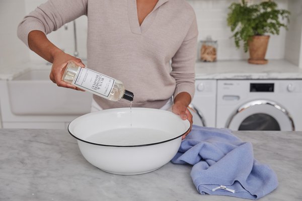 Caring for Vintage Pieces: Essential Tips for Preserving Timeless Treasures 2 pouring the laundress wool and cashmere shampoo in white enamel basin