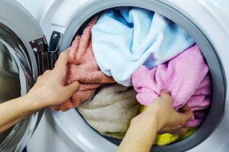shutterstock_564006334-800x534-1 Clothes being loaded into a washing machine.
